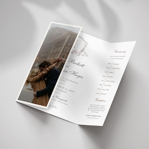 May include: A folded wedding invitation with a photograph of a couple embracing. The invitation features the names "Beckett and Hayes" and event details. The design is minimalist with elegant typography and floral accents.