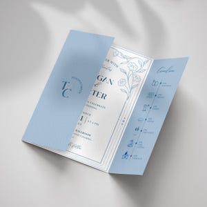 Puede incluir: Una invitación de boda azul claro, diseño tríptico, con ilustraciones florales y de línea de tiempo. La invitación incluye los nombres "Teagan & Carter" y detalles del evento. El diseño es elegante y formal.