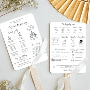 以下が含まれることがあります： 黒の文字とイラストが描かれた白い結婚式プログラムの扇子。表には、結婚式パーティー、式典の詳細、重要な人物が記載されています。裏には、結婚式当日のタイムライン、カップルの興味に関する詳細、ゲストの統計が記載されています。