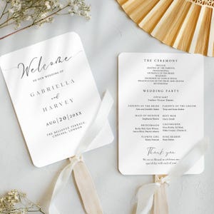 May include: White wedding program fan with a white ribbon. The front of the fan says "Welcome to our wedding of Gabriella and Harvey Aug 20 20XX The Bellevue Terrace, Chelsea, London". The back of the fan lists the wedding ceremony and reception details, including the officiant, parents of the bride and groom, maid of honor, best man, bridesmaids, groomsmen, flower girl, and ring bearer. The fan also includes the text "Thank you. We are so blessed to celebrate our special day with each of you!"