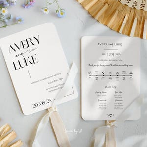 Może przedstawiać: Dwa białe programy weselne z uchwytami z kremowej wstążki. Na wachlarzach widnieją imiona "Avery and Luke" czarną czcionką. Jeden wachlarz zawiera datę i miejsce ślubu.