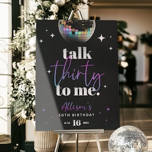 May include: A black sign on an easel with the text "talk thirty to me." The sign also includes the name "Allison's" and the date "June 16, 2021." Three disco balls are on the floor in front of the sign.