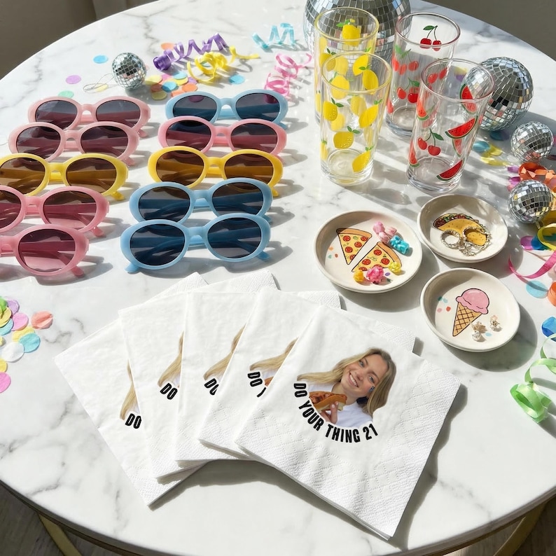 May include: A collection of party supplies including sunglasses, decorative glasses, small decorative plates, and napkins. The sunglasses are in pink, yellow, and blue. The glasses have lemon, cherry, and watermelon designs. The napkins have the text "DO YOUR THING 21".