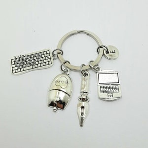 Può includere: Portachiavi in ​​argento con una varietà di ciondoli, tra cui una tastiera per computer, un mouse con la parola "LOVE" su di esso, una penna, un laptop e un ciondolo con la lettera "E".