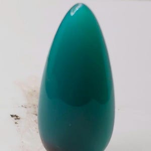 May include: A teardrop-shaped, teal-colored object with a glossy finish. The object has a smooth surface and a gradient effect, transitioning from a lighter teal at the top to a darker shade at the bottom. The object is set against a white background.