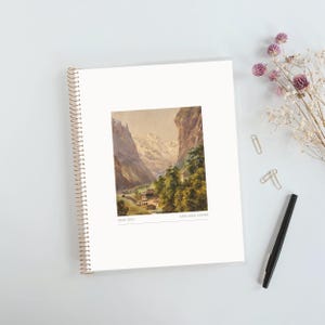 May include: A white spiral-bound notebook featuring a centered rectangular print of a mountain landscape painting with snow-capped peaks, trees, and a small building. The text 2026-2027 and MISS SARA ADKINS is printed in small grey font below the image.