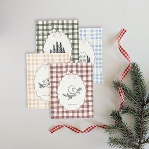 May include: Four rectangular greeting cards with gingham patterns in green, blue, beige, and maroon. Each card features a central scalloped oval frame with a bow, containing black line drawings of trees, a house, a cat, and a bird with the text peace & joy.