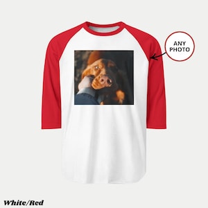 Pu&ograve; includere: Maglietta da baseball bianca e rossa con la foto di un cane. La maglietta ha il corpo bianco e le maniche rosse. La foto sulla maglietta &egrave; di un cane marrone che viene accarezzato. Il testo "ANY PHOTO" &egrave; in un cerchio rosso.