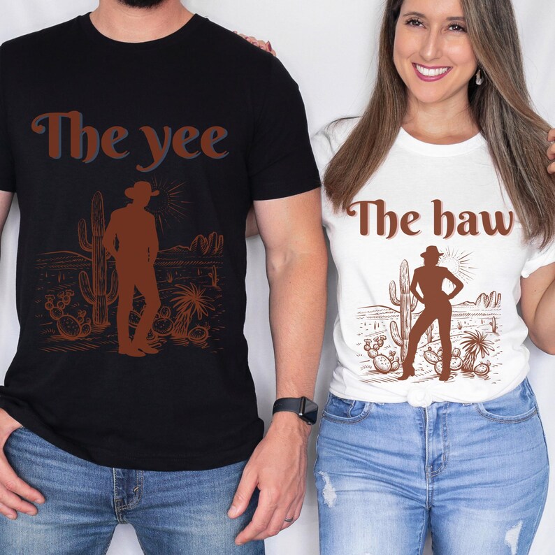 Op de afbeelding: Zwarte en witte T-shirts met een bruine afbeelding van een cowboy in een woestijnlandschap. Het zwarte shirt heeft "The yee" en het witte shirt "The haw" in bruine tekst. De shirts worden door twee personen gedragen.