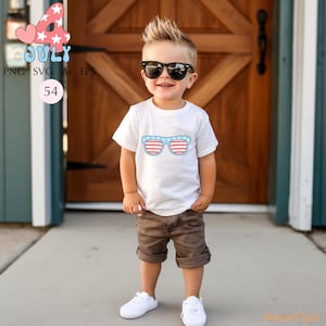 Puede incluir: Un ni&ntilde;o peque&ntilde;o con una camiseta blanca con un gr&aacute;fico de gafas de sol en rojo, blanco y azul. El ni&ntilde;o tambi&eacute;n lleva pantalones cortos marrones, zapatillas blancas y gafas de sol negras. La imagen incluye el texto "4 July" y "54".