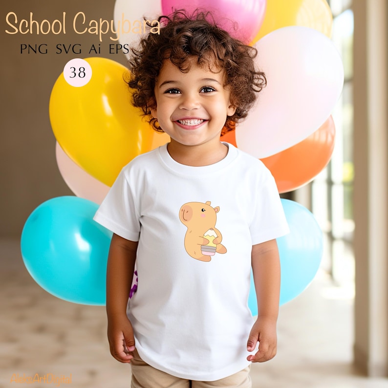 May include: A white t-shirt featuring a cartoon capybara holding a cupcake. The shirt has the text "School Capybara" at the top. A child is wearing the shirt and smiling, with colorful balloons in the background.