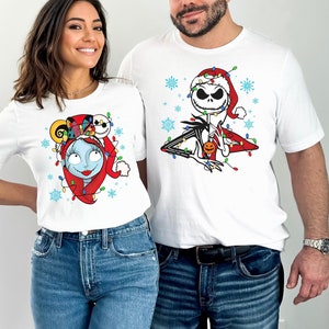 Puede incluir: Una camiseta blanca con un gr&aacute;fico navide&ntilde;o de Jack Skellington de Pesadilla antes de Navidad. El gr&aacute;fico presenta a Jack Skellington con un gorro de Pap&aacute; Noel y rodeado de luces navide&ntilde;as. La camiseta la lleva puesta una persona.