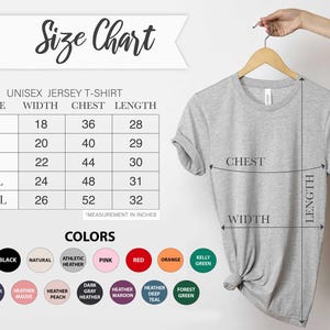 May include: A light grey unisex jersey t-shirt on a wooden hanger. The image shows a size chart with measurements in inches and a colour chart with options like white, black, and red. The text "Size Chart" is at the top of the image.