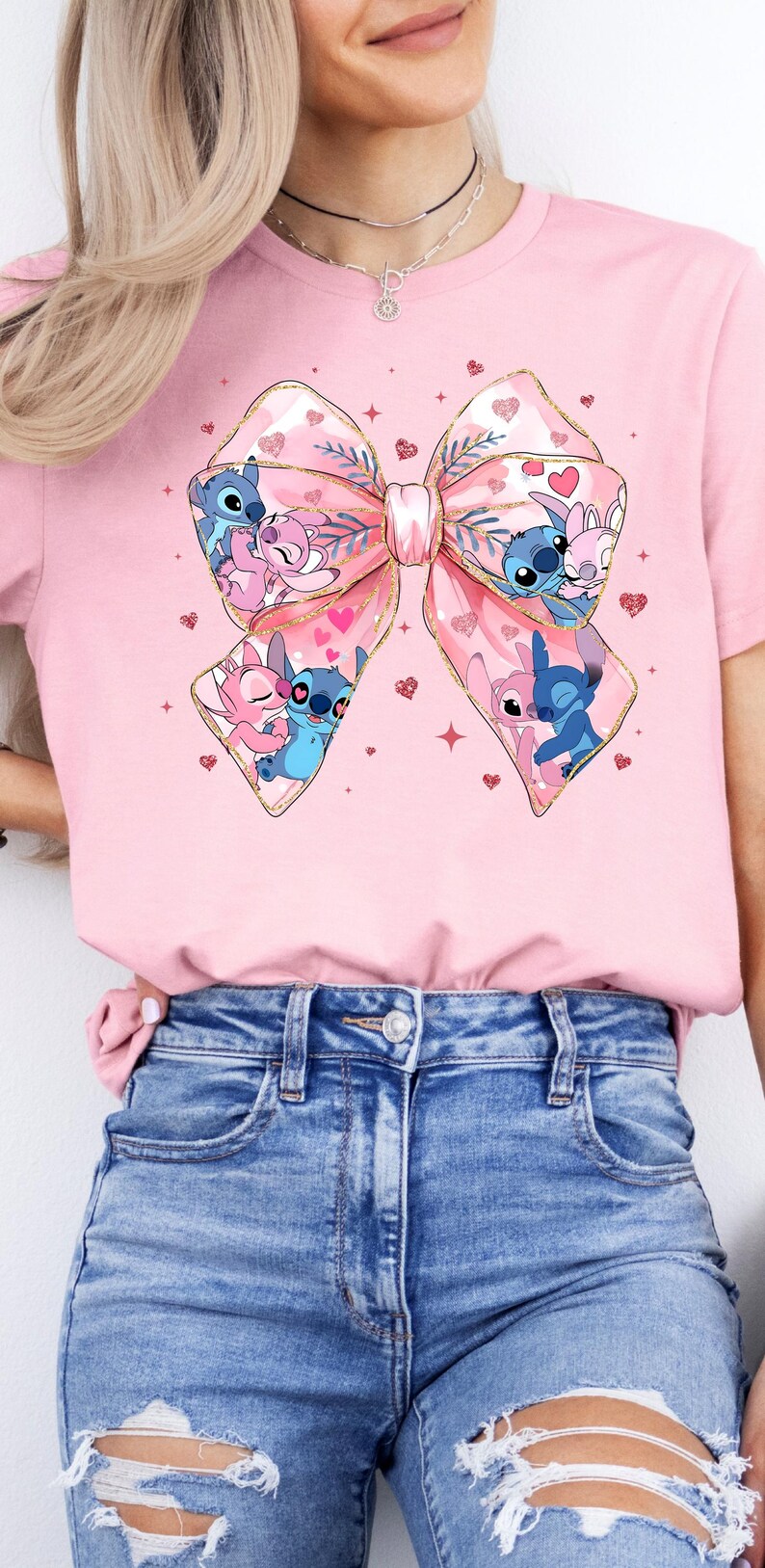 Peut inclure: T-shirt rose avec un grand n&oelig;ud rose avec des paillettes dor&eacute;es et un couple de personnages Stitch &agrave; l'int&eacute;rieur. Les personnages Stitch sont bleus et roses et s'embrassent. L'arri&egrave;re-plan est rose avec de petits c&oelig;urs roses et des paillettes dor&eacute;es.