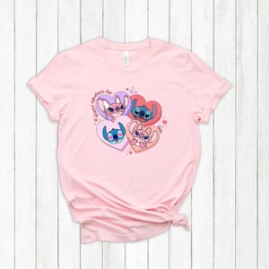 Puede incluir: Camiseta rosa con un gr&aacute;fico de cuatro personajes de Stitch de Lilo & Stitch en corazones. El texto "Happy Valentine's Day" est&aacute; escrito en un c&iacute;rculo alrededor de los corazones.