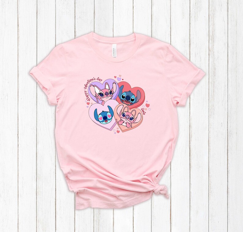 Puede incluir: Camiseta rosa con un gr&aacute;fico de cuatro personajes de Stitch de Lilo & Stitch en corazones. El texto "Happy Valentine's Day" est&aacute; escrito en un c&iacute;rculo alrededor de los corazones.