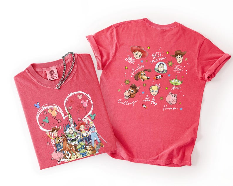 May include: Two red t-shirts featuring Disney's Toy Story characters. One shirt has a Mickey Mouse head design with characters like Woody, Buzz Lightyear, and others. The second shirt displays various Toy Story characters with their names.