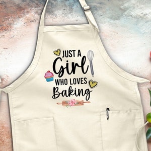 May include: A white apron with a pocket and adjustable straps. The apron has a black graphic that says "Just a Girl Who Loves Baking" with a cupcake, whisk, and rolling pin.
