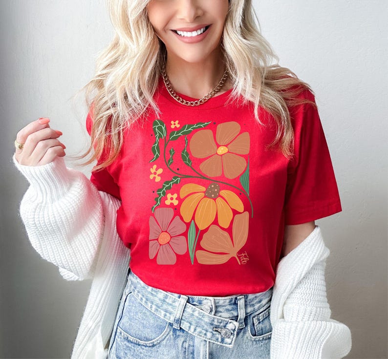 May include: Red t-shirt with a floral design featuring orange, brown, and pink flowers. The flowers are stylized and have a retro feel.
