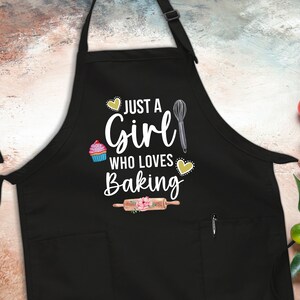 May include: Black apron with a white graphic that says "Just a Girl Who Loves Baking". The graphic includes a cupcake, a rolling pin, a whisk, and hearts.