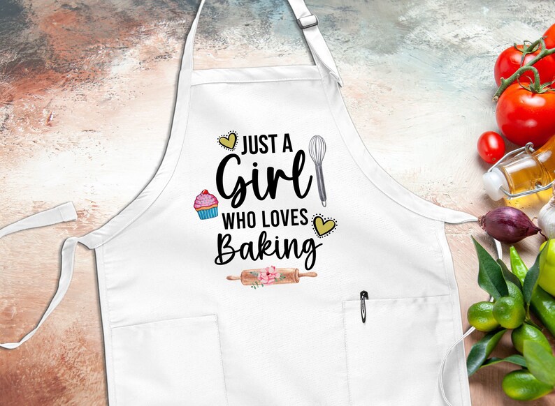 May include: White apron with a pocket and the text "Just a Girl Who Loves Baking" with a cupcake, whisk, and rolling pin graphic.