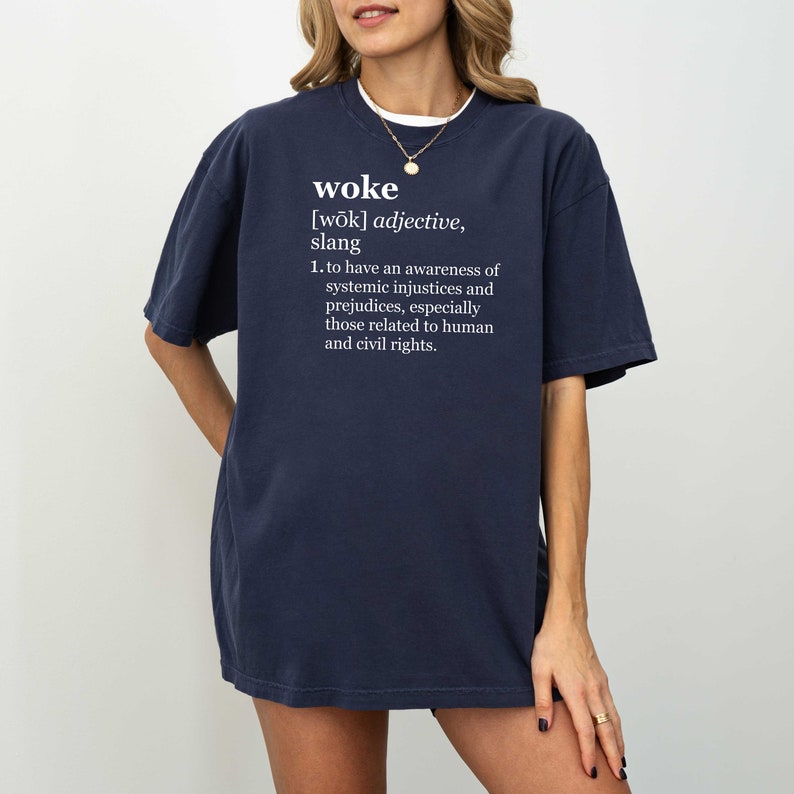 May include: A navy blue t-shirt with the word "woke" and its definition printed in white text.