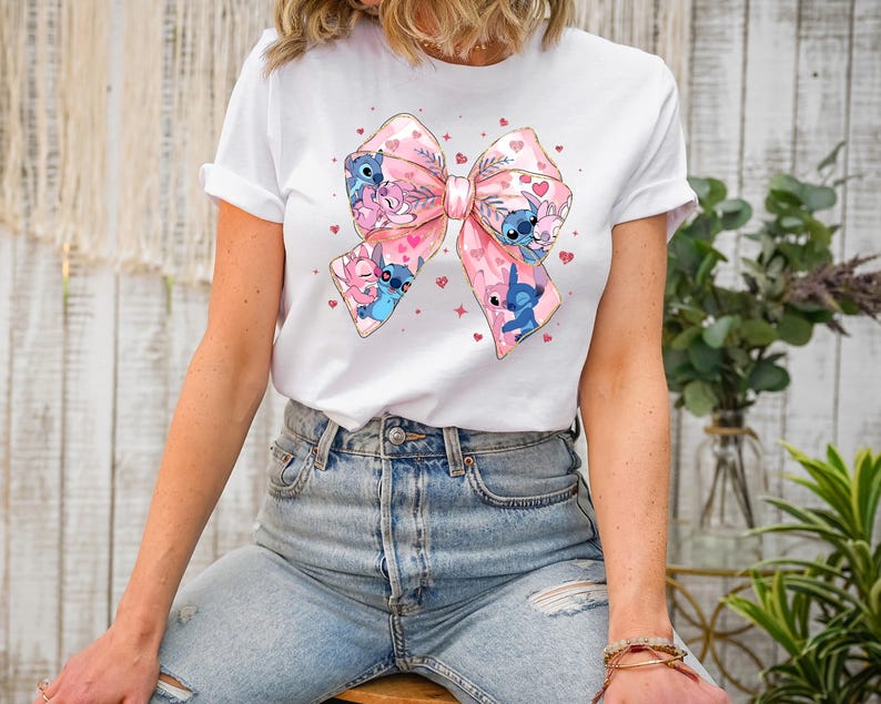 Peut inclure: T-shirt blanc avec un n&oelig;ud rose et bleu orn&eacute; de personnages de dessins anim&eacute;s. Le n&oelig;ud est d&eacute;cor&eacute; de c&oelig;urs et d'&eacute;toiles.