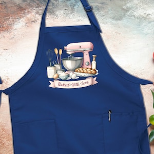 May include: Blue kitchen apron with a pocket and a white graphic of a pink stand mixer, ingredients, and bread with the text "Baked With Love".
