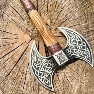 May include: A double-headed axe with a wooden handle wrapped in brown leather. The axe heads are decorated with intricate Celtic knotwork designs.