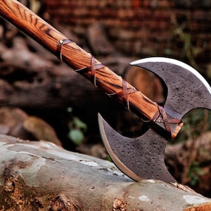 以下が含まれることがあります： 木製の柄に茶色の革が巻かれた両刃の斧。斧の頭は金属製で、濃いグレーの仕上げになっている。