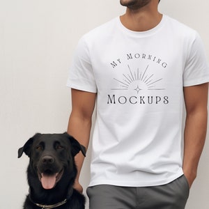 Può includere: Un uomo indossa una maglietta bianca con il testo "MY MORNING MOCKUPS" e un cane nero in piedi accanto a lui.