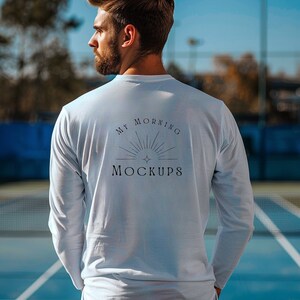 May include: A white long-sleeve shirt with the text "My Morning Mockups" printed on the back. The shirt features a simple sunburst design with a star in the center.