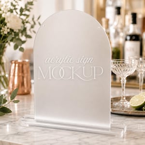Op de afbeelding: Een mat, boogvormig acrylbord met een doorzichtige rechthoekige voet. Het bord is voorzien van de wit gedrukte tekst "acrylic sign MOCKUP" in het midden van de voorzijde. Het materiaal heeft een gladde, matte afwerking en een semi-transparante uitstraling.