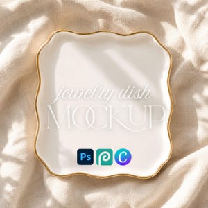 May include: A square white jewelry dish with a scalloped edge and a gold-colored rim. The center features the text "jewelry dish MOCKUP" in white, with three small square icons below in blue, teal, and purple, representing Ps, P, and C.