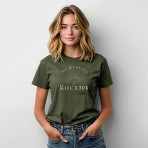 以下が含まれることがあります： オリーブグリーンのTシャツ。白い文字で「MY MORNING MOCKUPS」と書かれています。金髪の女性が着ています。Tシャツはクルーネックで半袖です。