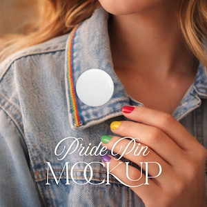 Op de afbeelding: Een witte, ronde Pride pin mockup op een spijkerjasje met een regenboogafwerking. De nagels van de persoon zijn in regenboogkleuren geverfd. De tekst "Pride Pin MOCKUP" wordt in een cursief lettertype weergegeven.
