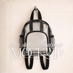 Puede incluir: Una mochila de plástico transparente con ribetes negros, correas ajustables negras, un asa superior y dos bolsillos laterales de malla. La parte frontal de la bolsa incluye un compartimento con cremallera. El texto "clear stadium backpack MOCKUP" es visible.