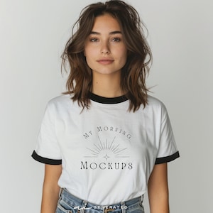 Könnte beinhalten: Ein weißes Ringer-T-Shirt mit schwarzem Besatz an Kragen und Ärmeln. Auf der Vorderseite befindet sich eine schwarze Grafik eines Sonnenaufgangs mit einem zentralen Stern und dem Text "MY MORNING MOCKUPS" in einer klaren Serifenschrift.