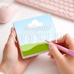 Könnte beinhalten: Notizblock-Mockup mit Landschaftsdesign mit blauem Himmel, weißen Wolken und grünen Hügeln. Die Worte "notepad MOCKUP" sind auf dem Bild überlagert. Ein rosa Stift wird in der Nähe des Notizblocks gehalten.