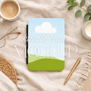 Puede incluir: Maqueta de funda Kindle con un diseño de cielo azul y paisaje verde. La funda presenta una nube blanca y las palabras "kindle case MOCKUP". Un bolígrafo dorado, una taza de café, gafas y una vela también están en la imagen.