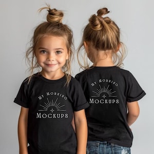 Op de afbeelding: Twee jonge kinderen dragen zwarte t-shirts met de tekst "MY MORNING MOCKUPS" in het wit. Het kind dat naar voren kijkt, lacht naar de camera. De t-shirts hebben een eenvoudig ontwerp met een zonnestraal.