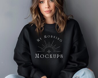 May include: A black long-sleeve sweatshirt featuring a white graphic print on the chest. The design includes a stylized sunburst icon with a central four-pointed star and the text MY MORNING MOCKUPS printed in a clean, white serif font.