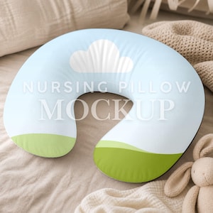 May include: A light blue nursing pillow with a white cloud design and green accents. The pillow has the words "NURSING PILLOW MOCKUP" printed on it. A stuffed bunny is in the background.