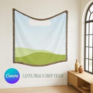 May include: A woven throw blanket featuring a landscape design with a light blue sky, a single white cloud, and rolling green hills. The blanket has a textured fringe border along all four edges and displays the text Canva Drag & Drop Frame.