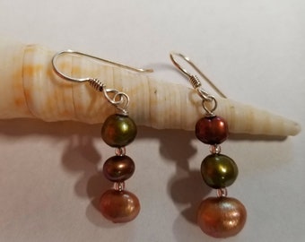 May include: A pair of silver dangle earrings with three brown and green pearls on each earring.