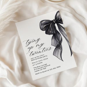 Pu&ograve; includere: Biglietto d'invito bianco con un'illustrazione di fiocco nero ad acquerello. Il biglietto presenta un'elegante calligrafia che recita "Tying up my twenties" e include i dettagli dell'evento per una festa di compleanno, come data, ora e luogo.