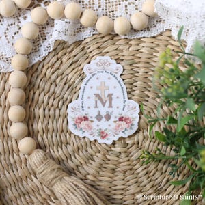 Puede incluir: Una pegatina blanca con un dise&ntilde;o floral y el texto "Oh Mar&iacute;a, concebida sin pecado, ruega por nosotros que recurrimos a ti" y una imagen estilizada de la Virgen Mar&iacute;a con una cruz y un coraz&oacute;n.