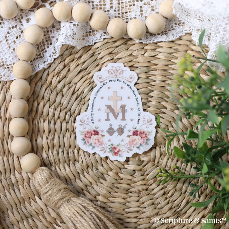 Puede incluir: Una pegatina blanca con un dise&ntilde;o floral y el texto "Oh Mar&iacute;a, concebida sin pecado, ruega por nosotros que recurrimos a ti" y una imagen estilizada de la Virgen Mar&iacute;a con una cruz y un coraz&oacute;n.