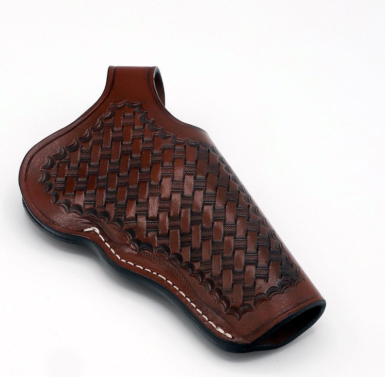 May include: A brown leather holster with a woven pattern. The holster has a white stitching detail around the edges.