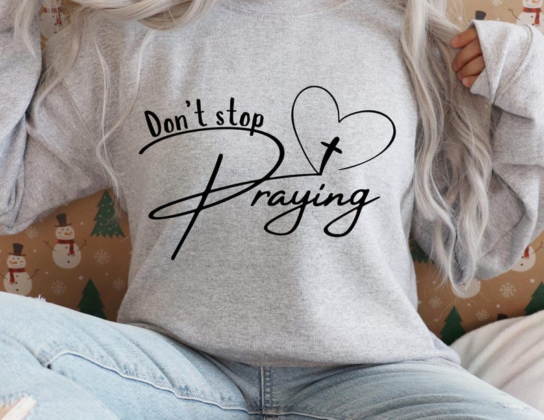 Peut inclure: Sweat-shirt gris avec le texte "Don't stop praying" et un c&oelig;ur avec une croix &agrave; l'int&eacute;rieur.